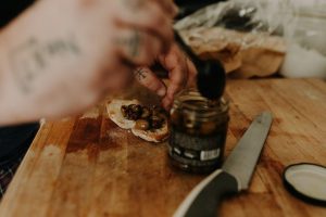 a person putting olives on a piece of bread