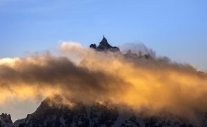 A mountain covered in clouds with a sky background